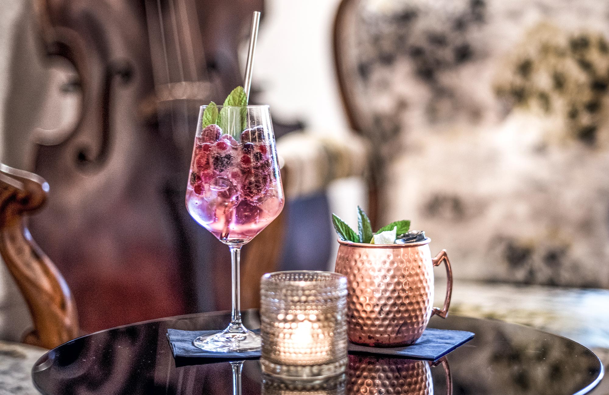 Two apertivi on a black table with a candle in front of it - Hotel Wieser