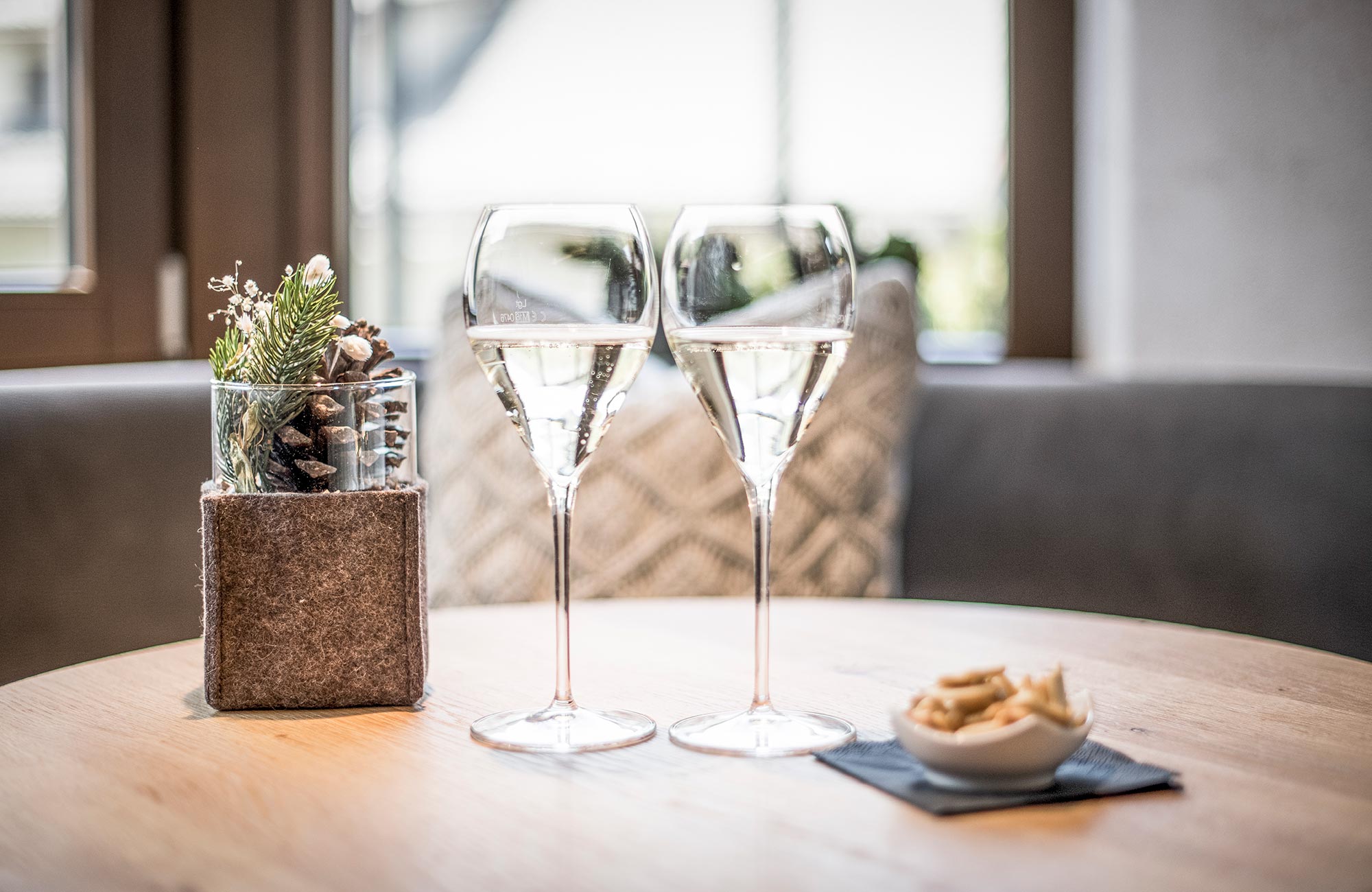 Two Prosecco glasses on a table with nuts and decoration next to them - Hotel Wieser