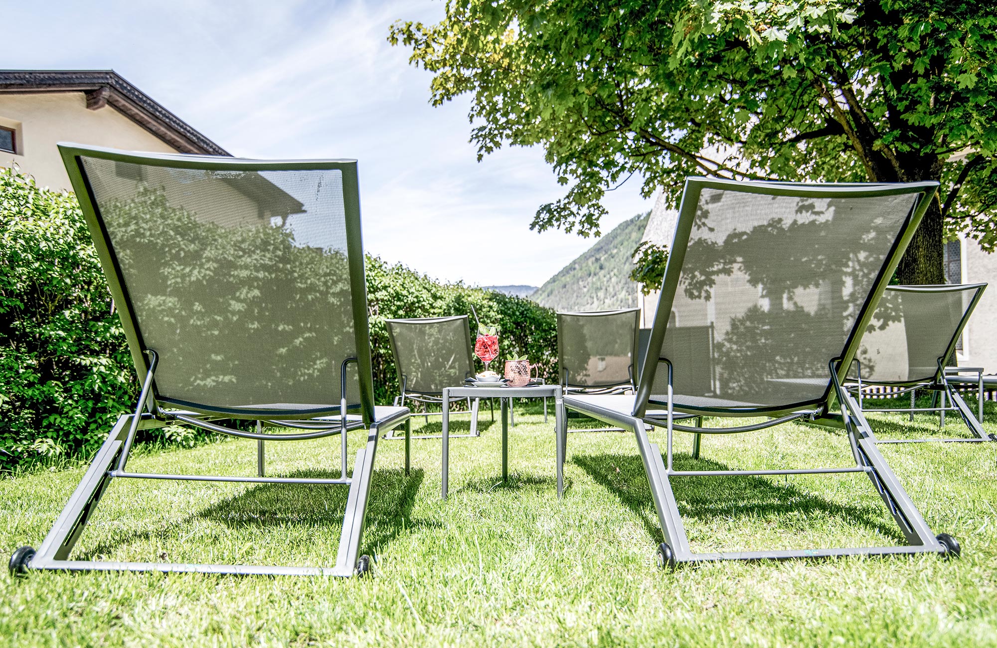 Sun loungers in the garden with two aperitivi on the table - Hotel Wieser