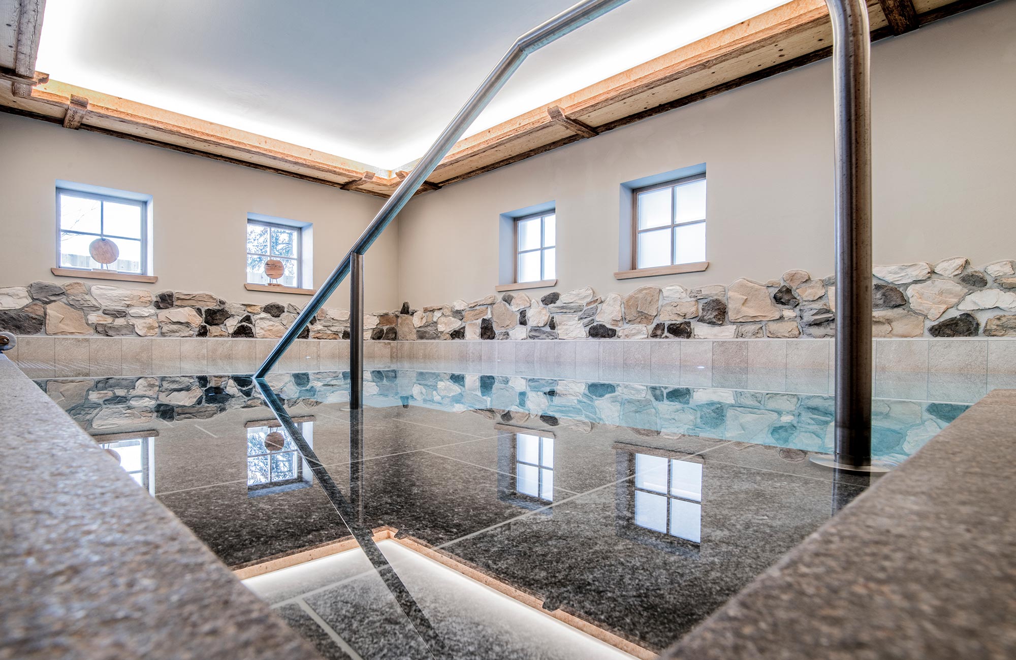 Pool with stone wall and four windows in the background - Hotel Wieser