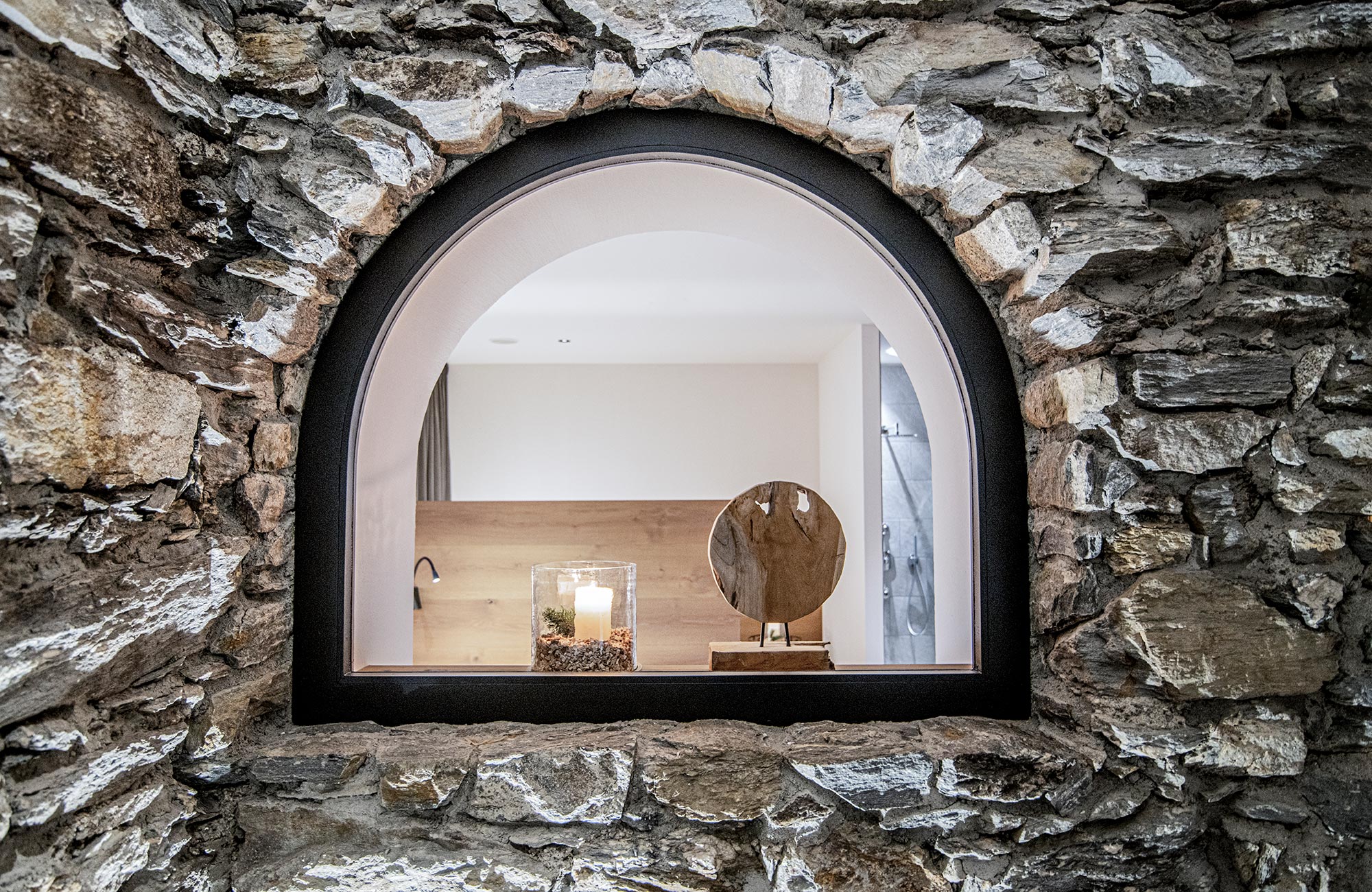 Stone wall with a window overlooking the wellness area - Hotel Wieser