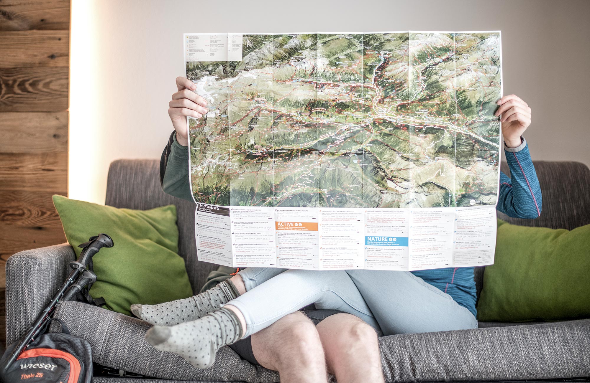 A couple sits on the sofa and hides behind the map - Hotel Wieser