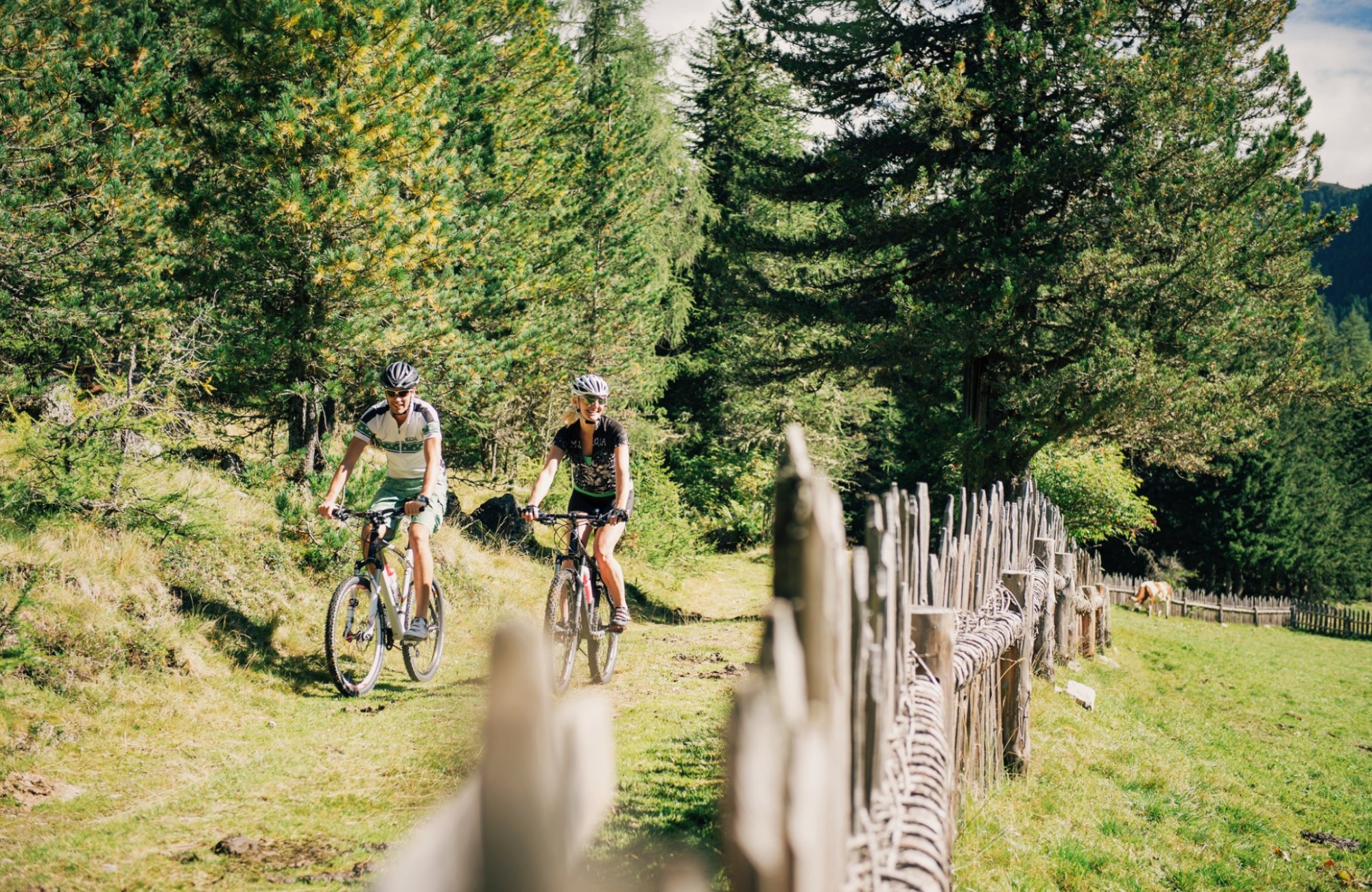 A couple cycling in the forest - Hotel Wieser