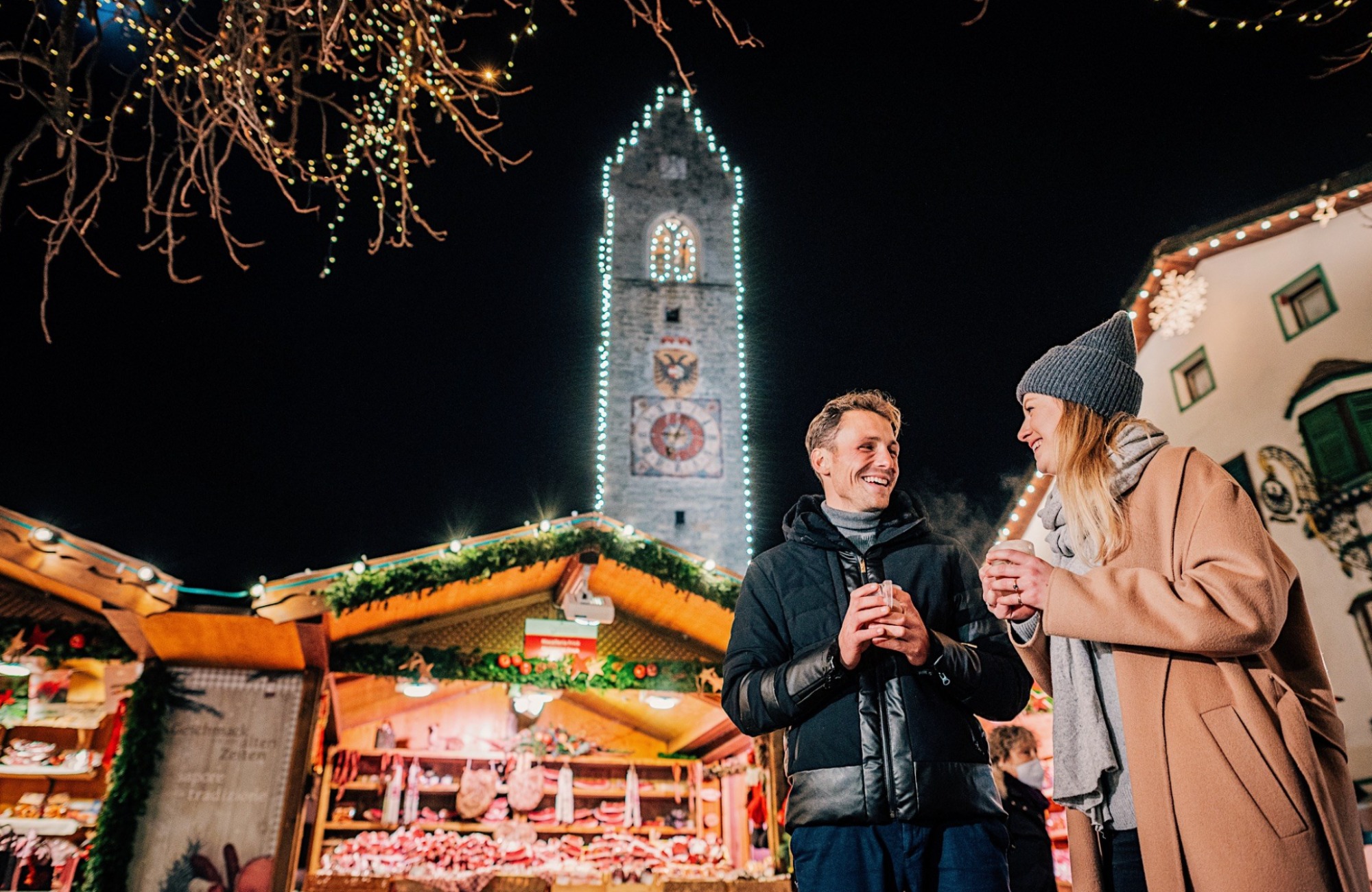 A couple stands in front of a stall at the Christmas market in Sterzing - Hotel Wieser