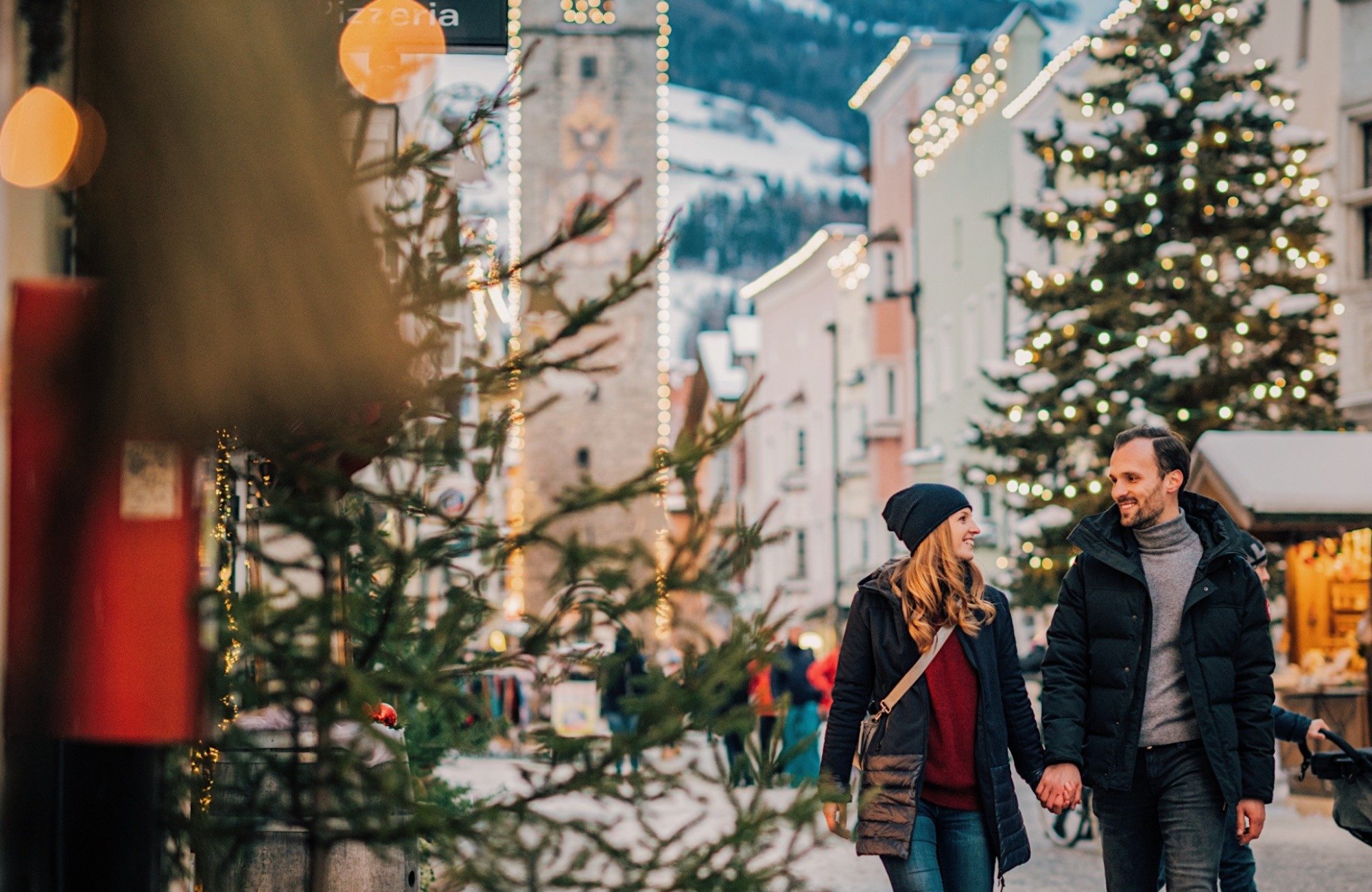 A couple at the Vipiteno Christmas market in front of the Zwölferturm - Hotel Wieser