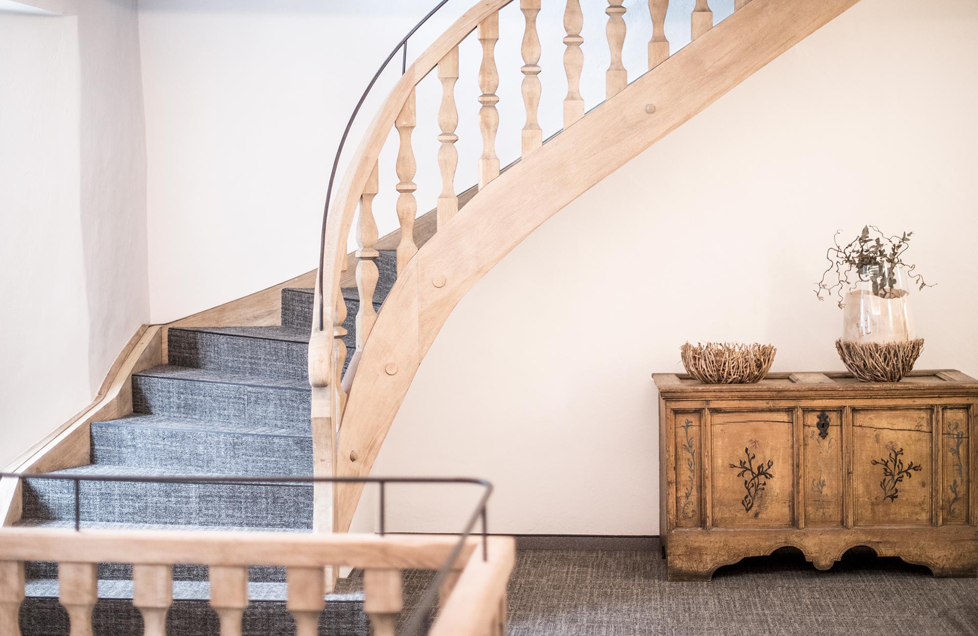 Hallway with wooden stairs and a wooden chest of drawers - Hotel Wieser