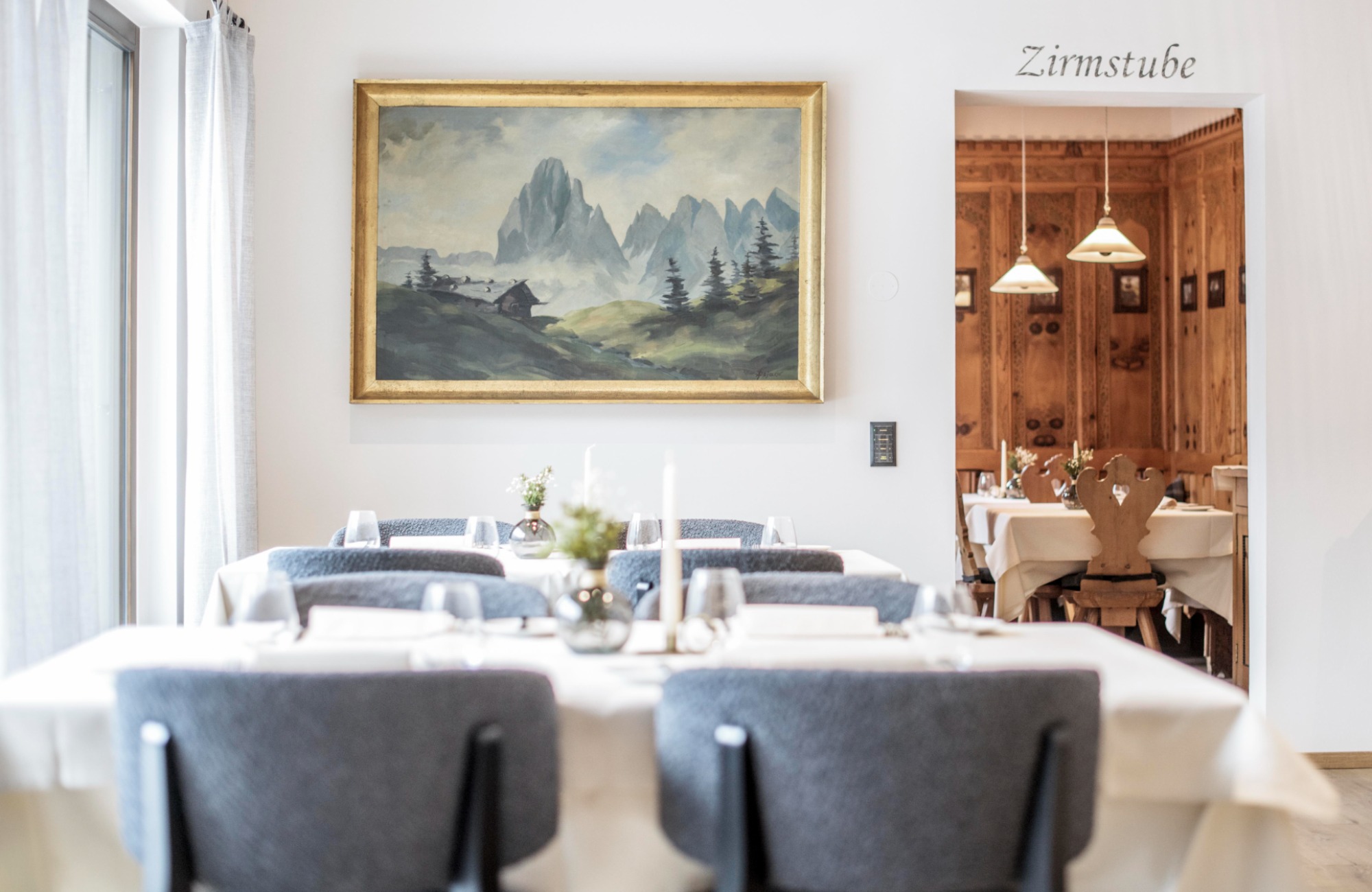 Dining room with two set tables and a large picture of mountains in the background - Hotel Wieser