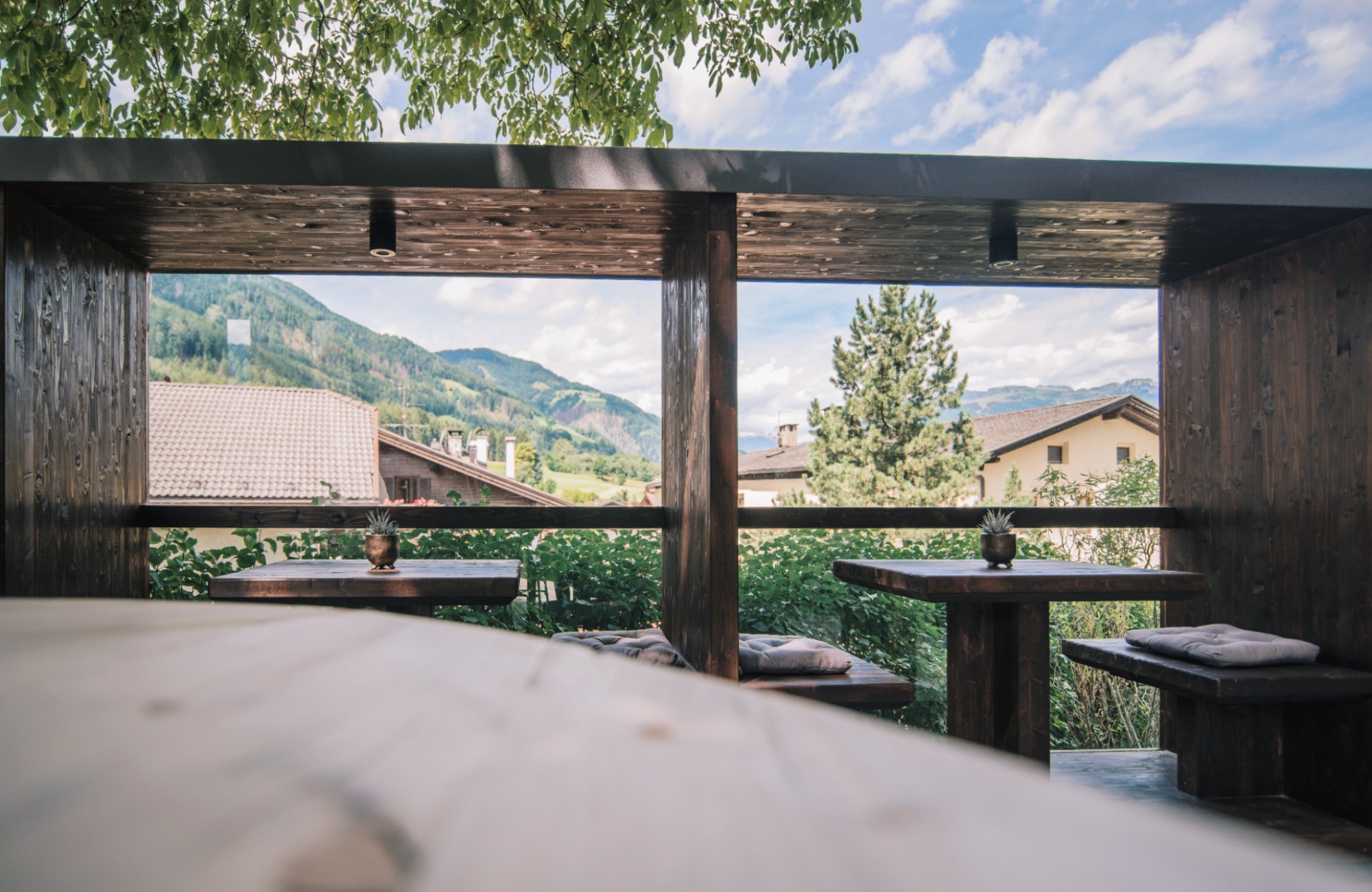Two wooden tables and four benches on the terrace - Hotel Wieser