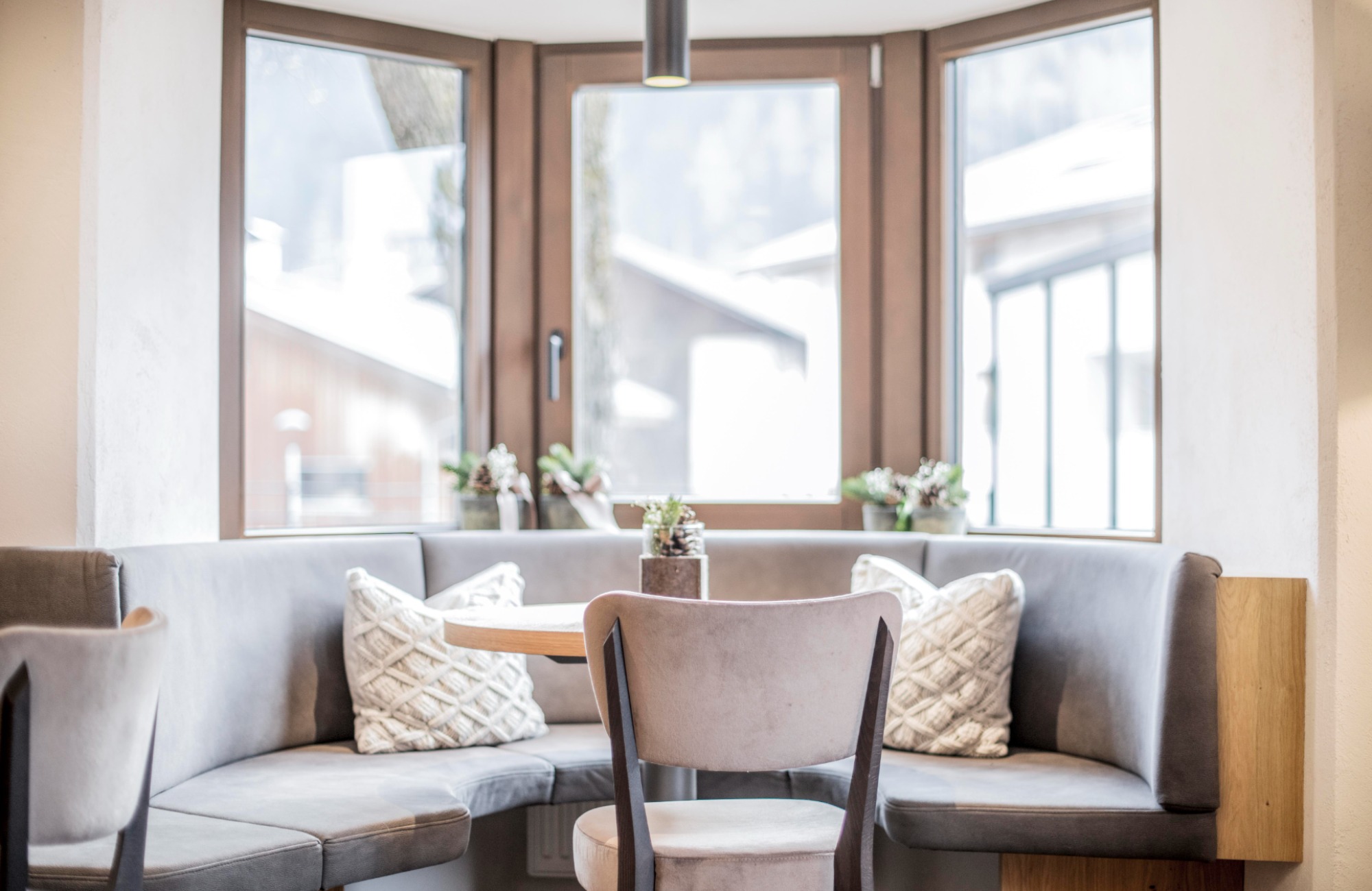 Table with gray chair, bench and white cushions - Hotel Wieser